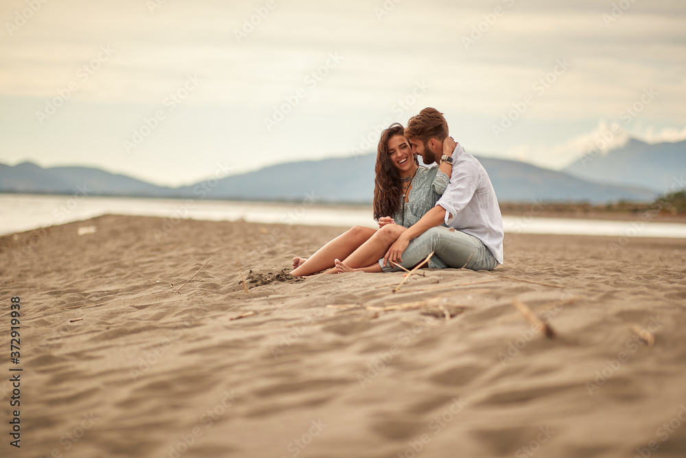 Young couple in love sitting in a hug on the beach