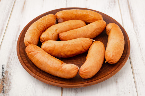 sausages on a plate on a white wooden background.