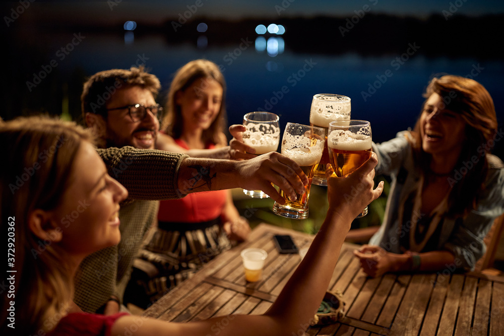 Φωτογραφία Group of friends having a toast wit the beer in the bar on the lake