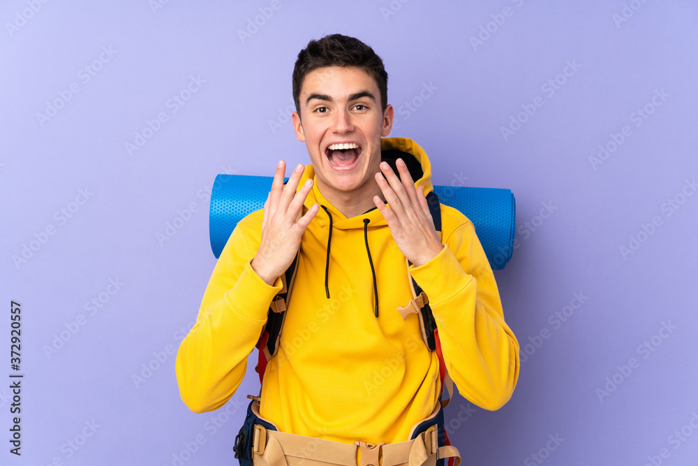 Teenager caucasian mountaineer man with a big backpack isolated on purple background with surprise facial expression Teenager caucasian mountaineer man with a big backpack isolated on purple background with surprise facial expression