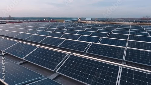 Rows of solar panels at sunlight. Photovoltaic solar cells on the modern electricity farm on flat roof. Renewable source of clean energy from the sun. Drone flight.