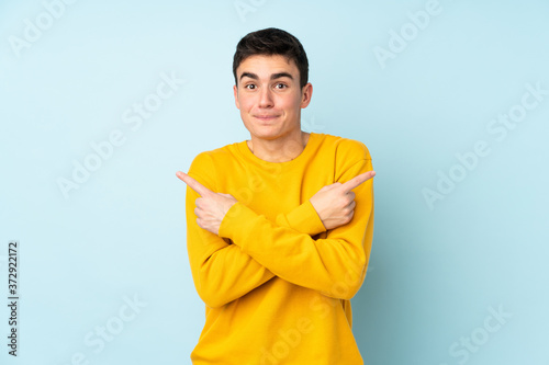 Teenager caucasian handsome man isolated on purple background pointing to the laterals having doubts