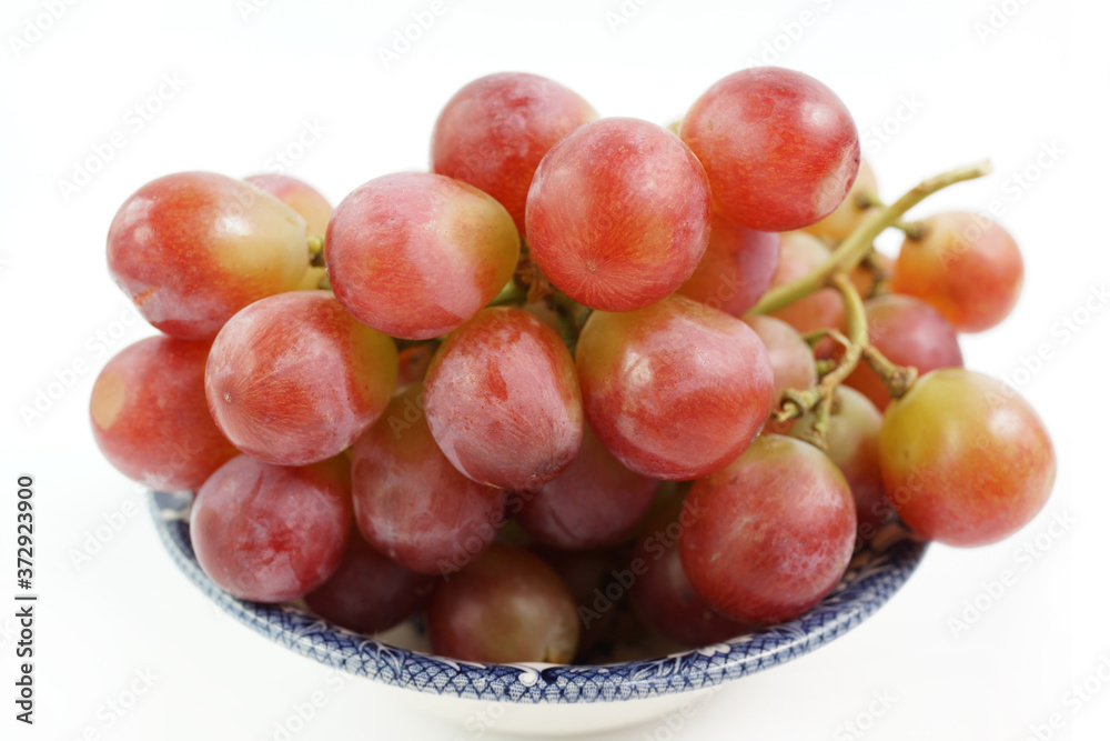 A bowl of red grapes on the vine, isolated on a white background A bowl of red grapes on the vine, isolated on a white background