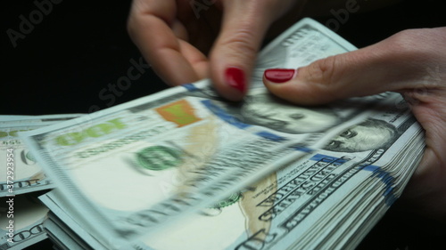 Unrecognizable business woman counting american cash money on black background