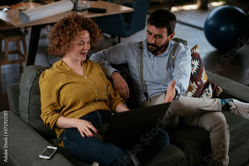 Businesswoman and businessman sitting and talking in office. Young woman and man working on laptop.
