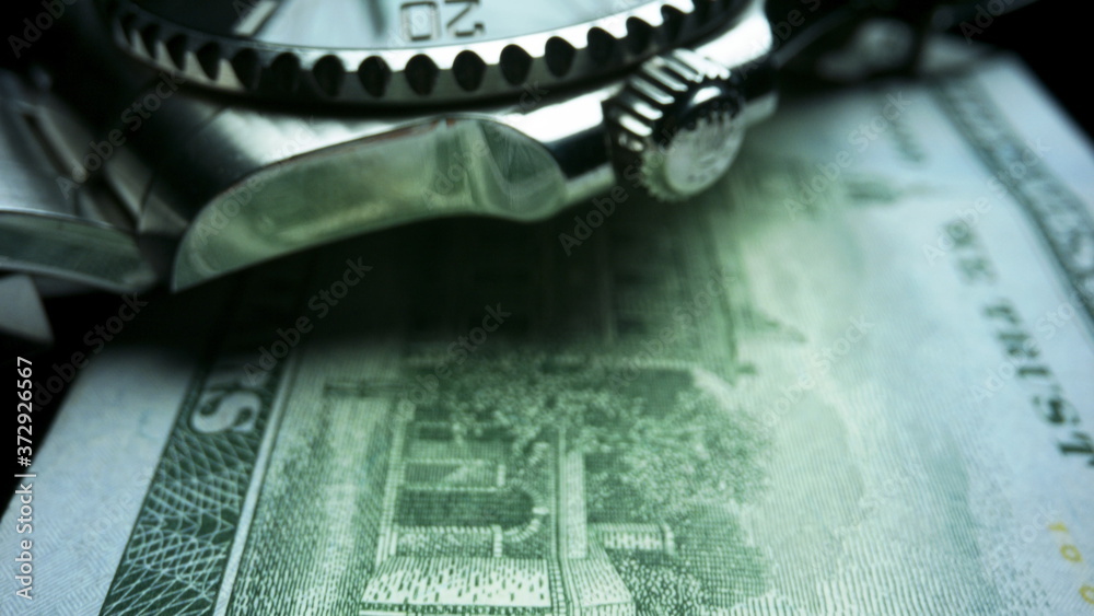 Wristwatch lying on one hundred dollar banknote. US cash money Wristwatch lying on one hundred dollar banknote. US cash money