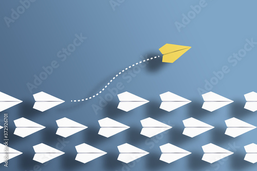 paper planes in a row on blue background and one paper glider going in different direction, breaking new ground and stepping out of the line concept photo