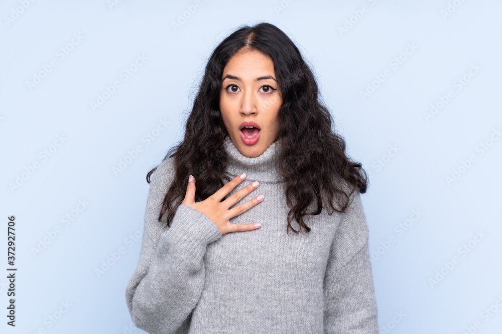 Spanish Chinese woman over isolated blue background surprised and shocked while looking right Spanish Chinese woman over isolated blue background surprised and shocked while looking right