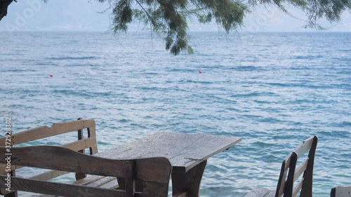 Empty table in the restaurant next to the beach, in the shade under the trees. In the background is Adriatic sea. Island of Brac, Croatia.
