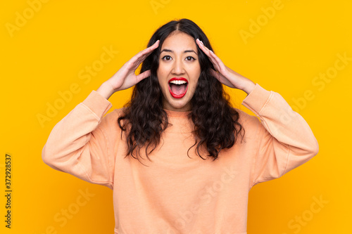 Spanish Chinese woman over isolated yellow background with surprise expression