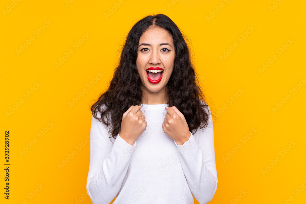 Mixed race woman over isolated yellow background celebrating a victory Mixed race woman over isolated yellow background celebrating a victory