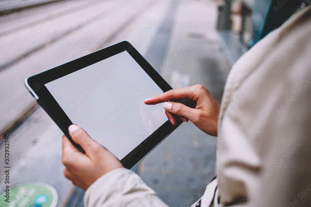 Cropped view of woman's hands holding modern touch pad device with blank screen area for your internet advertise or website content.Female person touching with finger mock up display on tablet