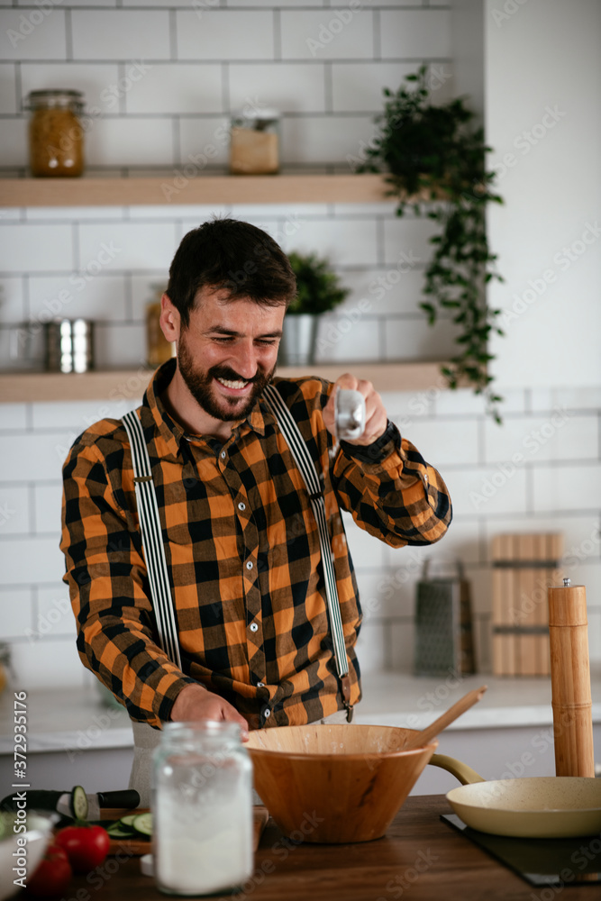 Portrait of handsome man in kitchen. Young man preparing delicious food.. Portrait of handsome man in kitchen. Young man preparing delicious food..