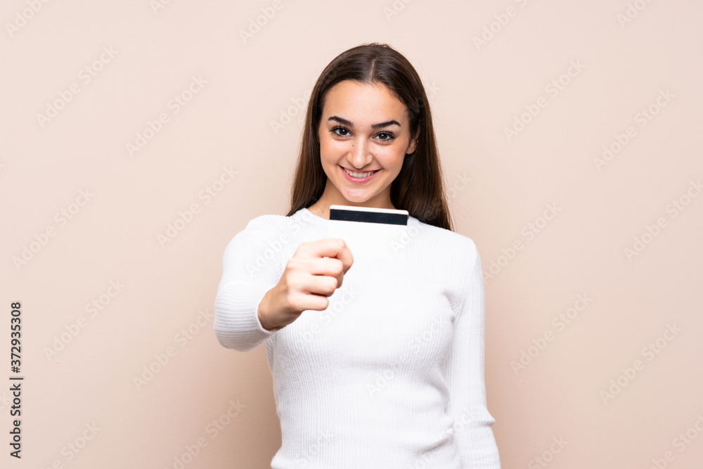 Young woman over isolated background holding a credit card Young woman over isolated background holding a credit card