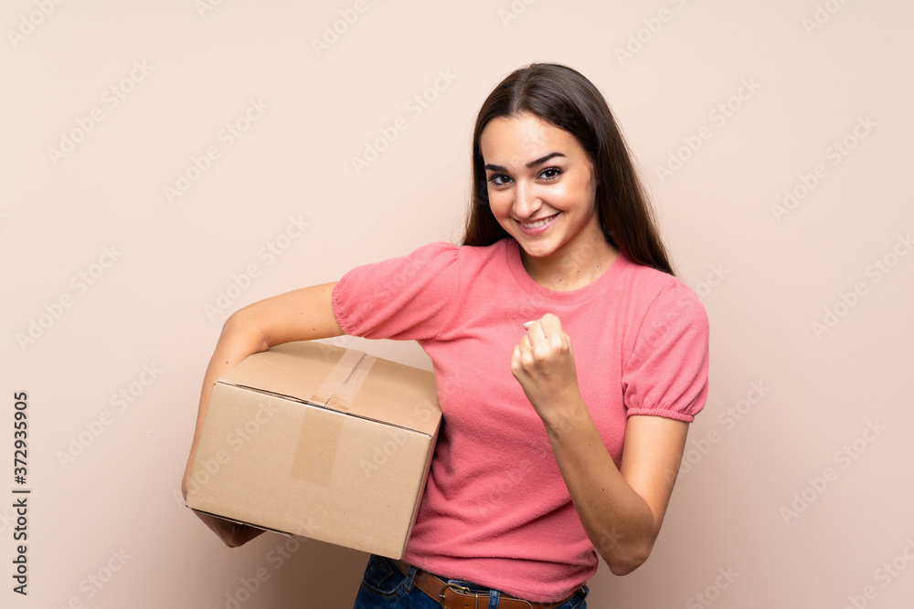 Young woman over isolated background holding a box to move it to another site Young woman over isolated background holding a box to move it to another site