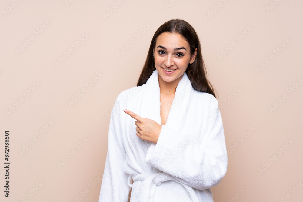 Young girl in a bathrobe over isolated background pointing finger to the side Young girl in a bathrobe over isolated background pointing finger to the side