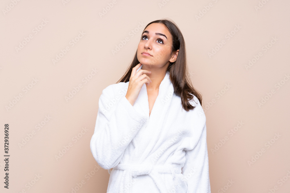 Young girl in a bathrobe over isolated background thinking an idea Young girl in a bathrobe over isolated background thinking an idea