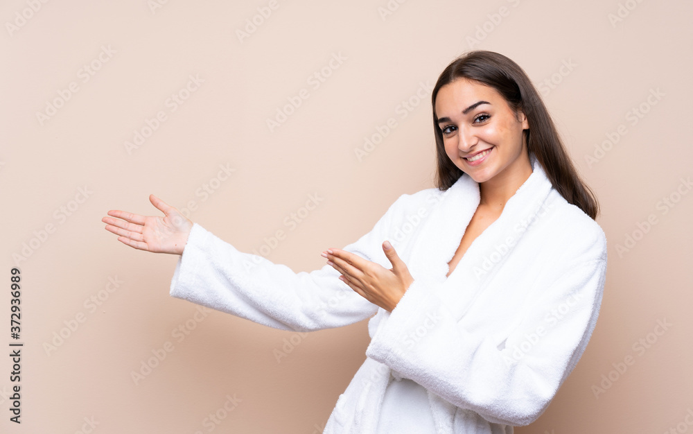 Young girl in a bathrobe over isolated background extending hands to the side for inviting to come Young girl in a bathrobe over isolated background extending hands to the side for inviting to come