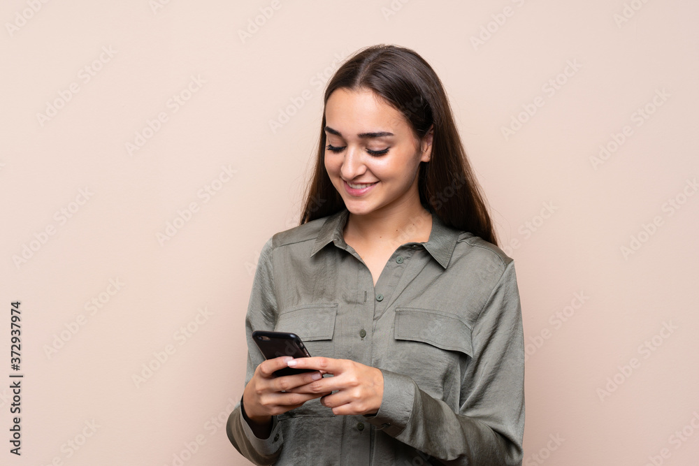 Young girl over isolated background sending a message with the mobile Young girl over isolated background sending a message with the mobile