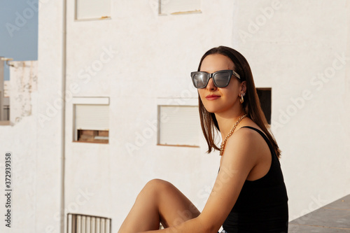 A traveler brunette girl is looking at the white buildings.Woman looking on the city. Back view of beautiful giel wearing sunglasses photo