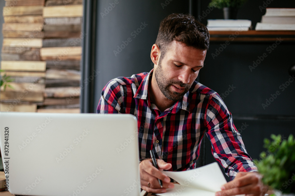 Young businessman in office. Businessman sitting at office desk working on laptop computer Young businessman in office. Businessman sitting at office desk working on laptop computer