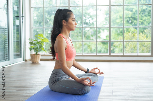 Young asian woman doing yoga exercises at home.