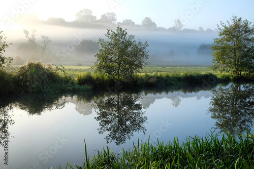 Early morning mist over the meadows on the River Wey in Godalming, Surrey, on a cold autumn morning.