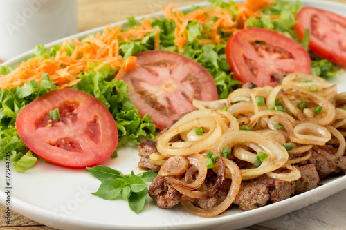 Comida de hotel - Close up Bife acebolado com salada de alface, tomate e cenoura	