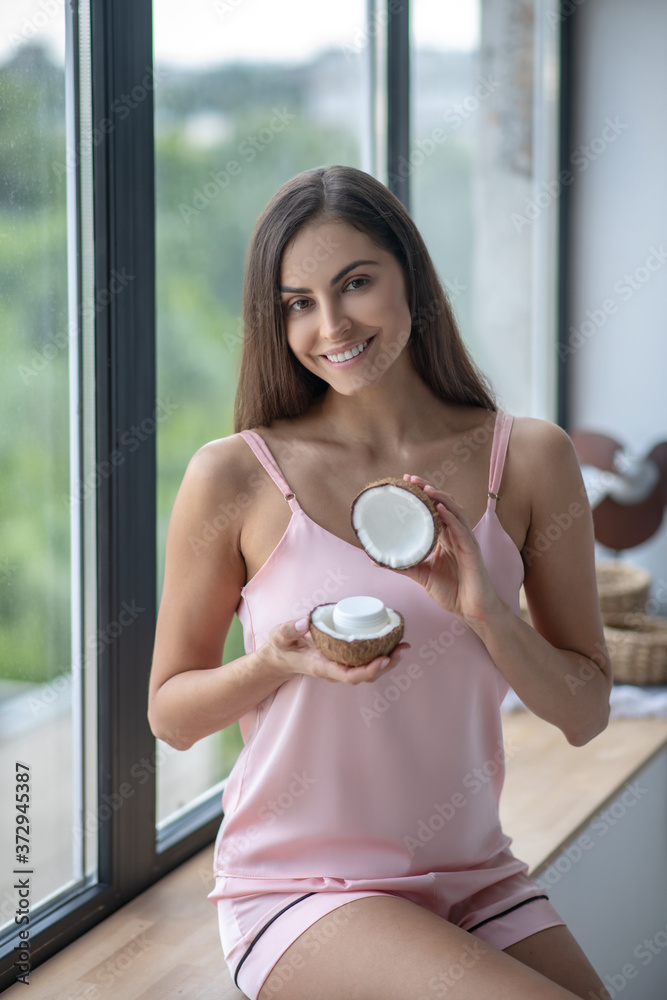Woman in pink lingerie holding cream in her hands