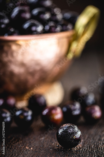 Jaboticaba or jabuticaba, Brazilian and South American fruit, in a copper pot on a rustic table. Fruit for medicinal and culinary use. Spot focus photo