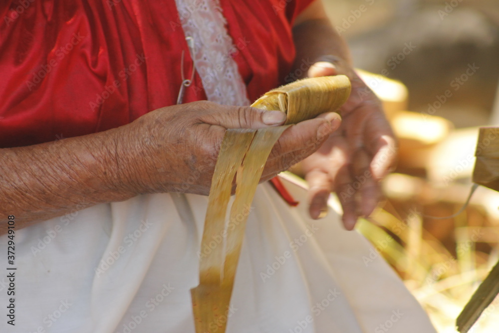 indigenous woman's hands wrapping tamale in corn husk mexican corundas