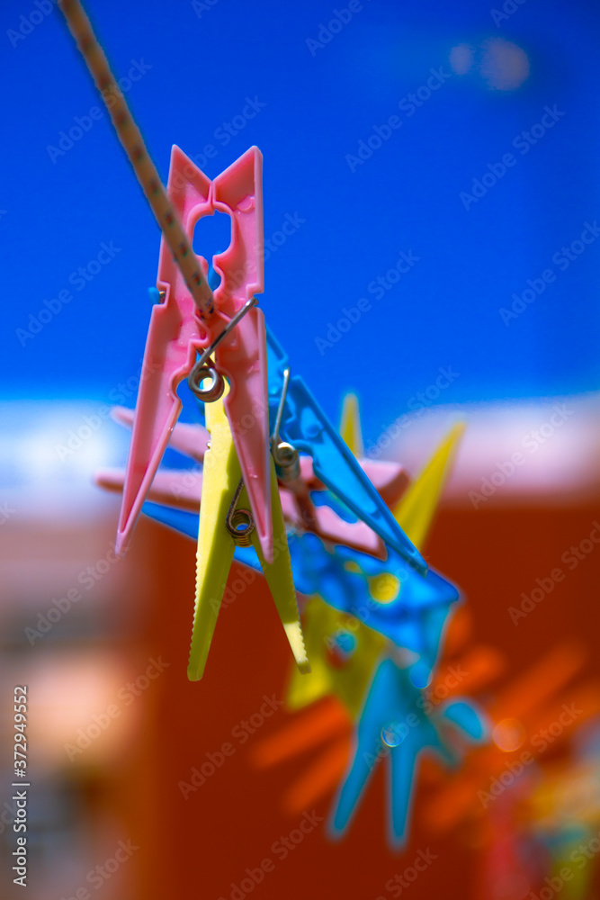 Coloured plastic clothespins fastened on a rope with the background out of focus