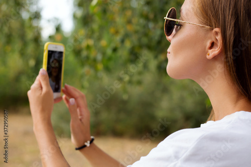 attractive woman sending air kiss while taking selfie on mobile phone