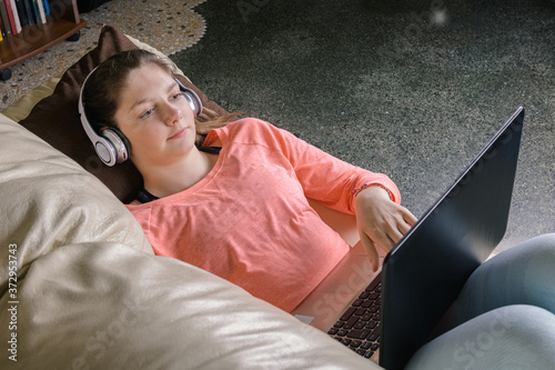 Smiling girl student wear wireless headphone comunicate or study online, happy young woman learn language listen lecture watch webinar, look at laptop, distant education and e-learning photo