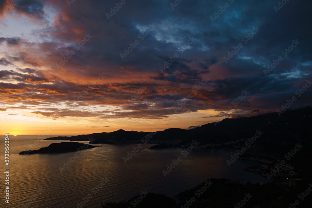 Fiery red and blue sky during sunset over the Budva Riviera in Montenegro and the island of St. Nicholas.