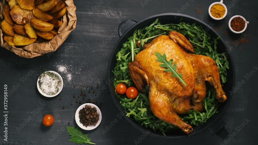 Roasted whole chicken or turkey served in iron pan Placed on black background Top view.