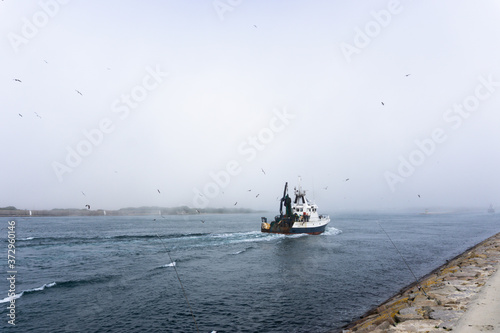 Fishing boat leaving port on a cloudy day