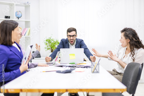 Photo of manager discussing something with his coworkers listening to him sitting at the office table.