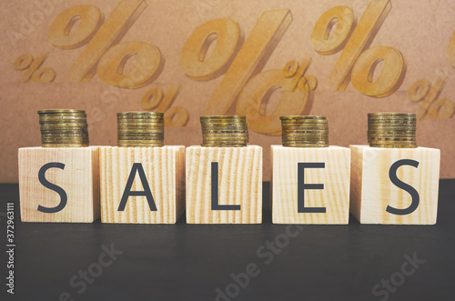 SALE word on wooden cubes, cubes stand on a black surface, in the background - a percent sign. Business and finance concept