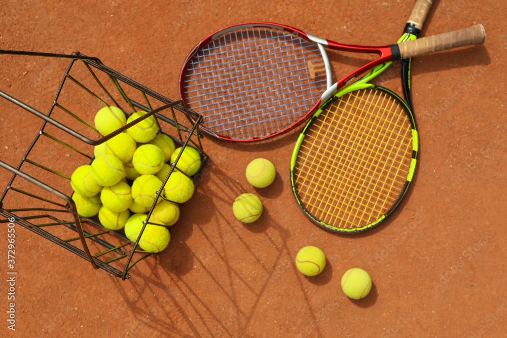 Racket and basket with balls on clay court