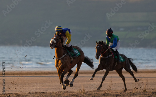Race horses and jockeys competing on the beach at sunset on the west coast of Ireland,
