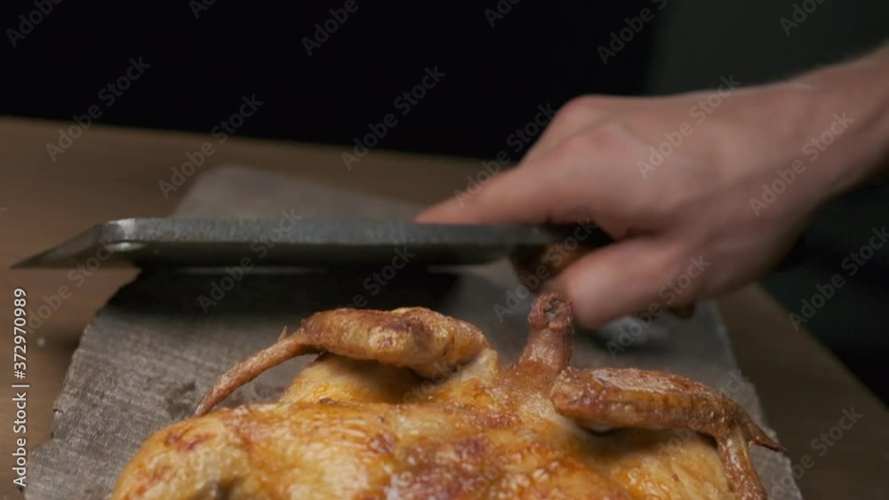 the chef prepares to cut a whole grilled chicken with a large knife, slow motion the chef prepares to cut a whole grilled chicken with a large knife, slow motion