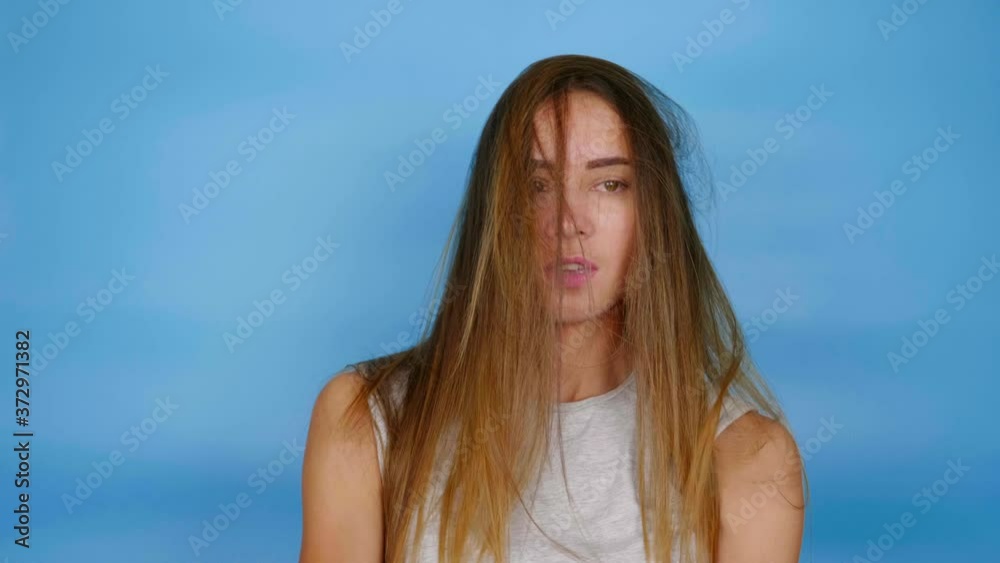 Beautiful funny woman in gray T-shirt is dancing on blue background with copy space. 4K slow motion footage Beautiful funny woman in gray T-shirt is dancing on blue background with copy space. 4K slow motion footage