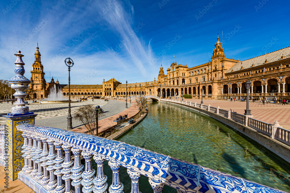 Plaza de Espana with its canal, blue mosaic bridge and its imposing building in the background, beautiful sunny day and a blue sky in the background in Spain