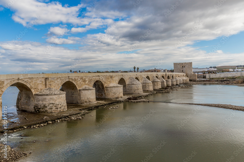 River Guadalquivir river and the Roman bridge of Cordoba in a wonderful day with a blue sky and white clouds in Spain