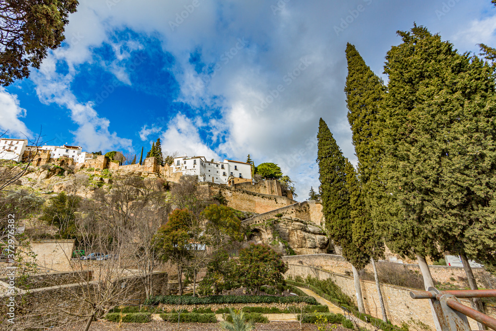 View of the city of Ronda on the plateau with its white buildings on top from a lower perspective, sunny day with abundant clouds in the province of Malaga, Spain