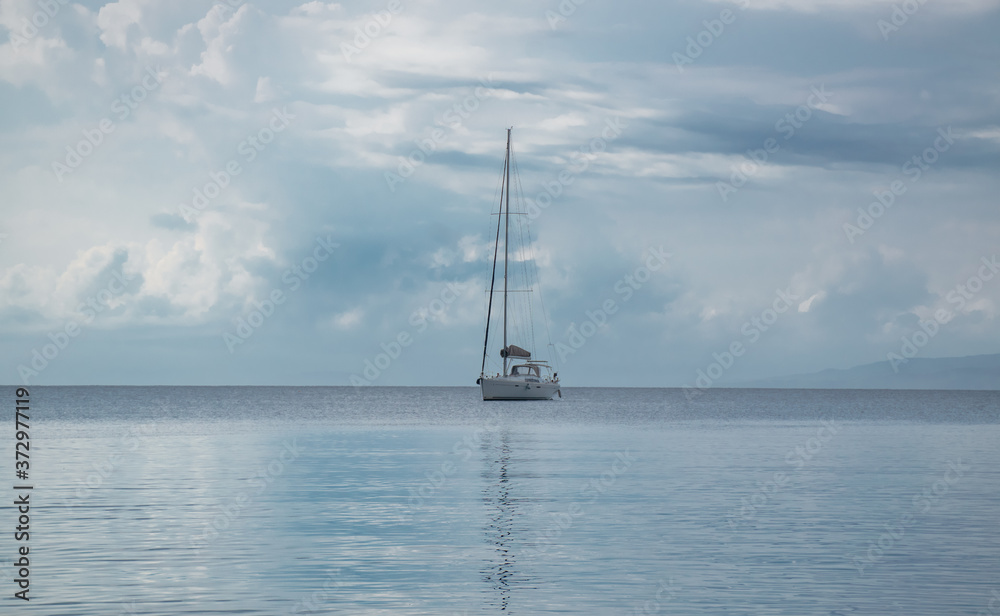 sailing boat on a calm sea, during a cloudy summer day sailing boat on a calm sea, during a cloudy summer day