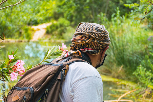 Adventurer man with backpack hiking in nature