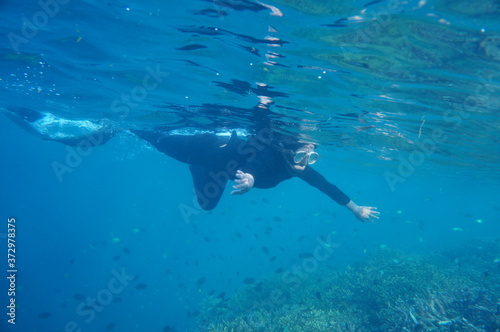 a lady with hijab / veil snorkeling in the sea