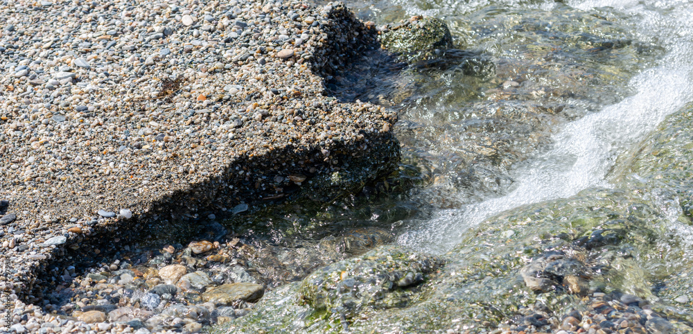 Obraz premium Clean water between the pebbles on the seashore